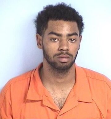 Mug shot of a black male with facial hair in an orange jumpsuit