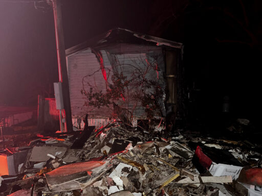 Side of mobile home at night with debris on the ground