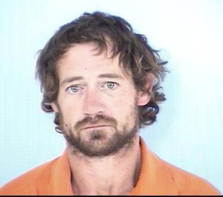 White male with shaggy brown hair and brown beard wearing orange jumpsuit