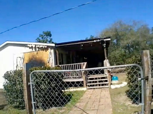 Side of mobile home with smoke damage and a large porch