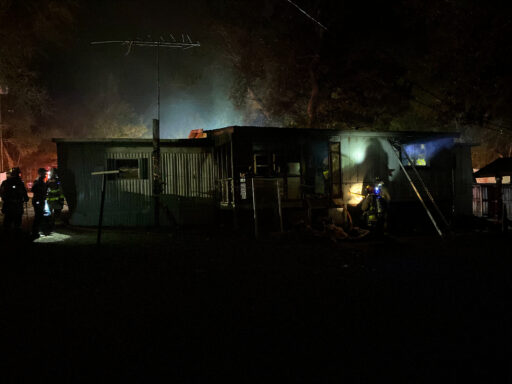 First responders outside of burning mobile home at night