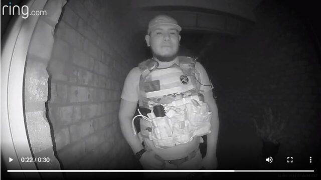 Video screen shot of a man with a tactical vest and ball cap