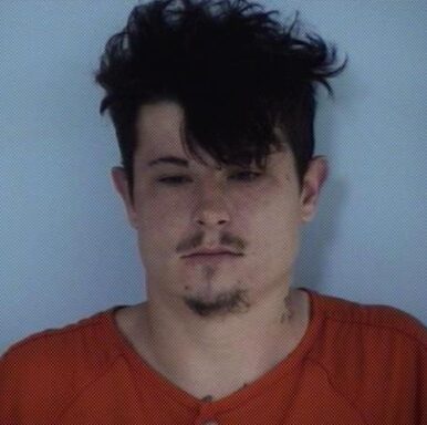 Mug shot of a white male with dark black hair and black facial hair. 