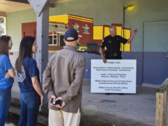 Deputy standing with a thank you sign pointing at a mural