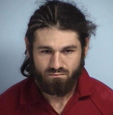Mug shot of a white male with corn rows on half of his head.