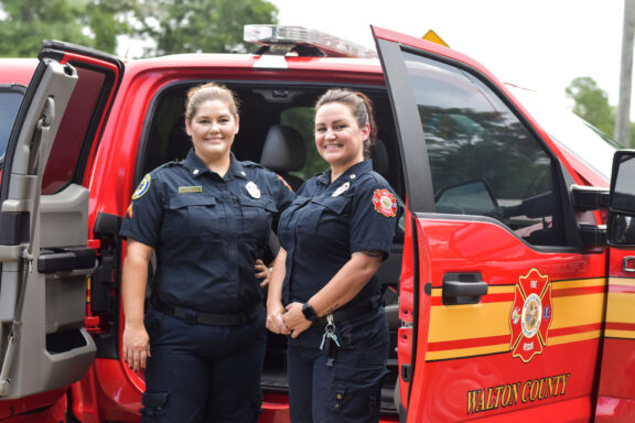 Two paramedics stand outside a Walton County Fire Rescue vehicle