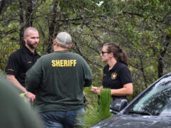 Three investigators talking near a crime scene