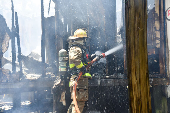 Firefighters extinguishing a house fire with a hose