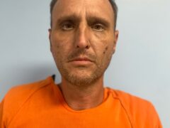 Mug shot of a while male with an orange jumpsuit.