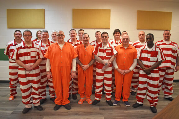 male inmates in orange or red and white striped jumpsuits
