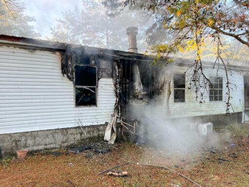 Smoke coming from charred mobile home following a structure fire