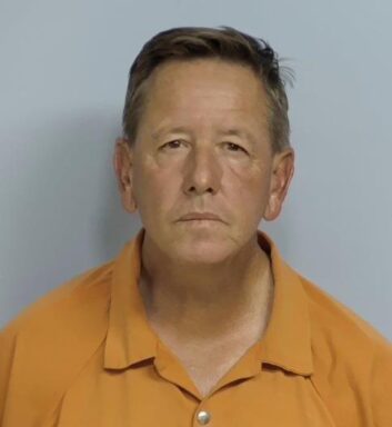 Mug shot of a white male in an orange jumpsuit.