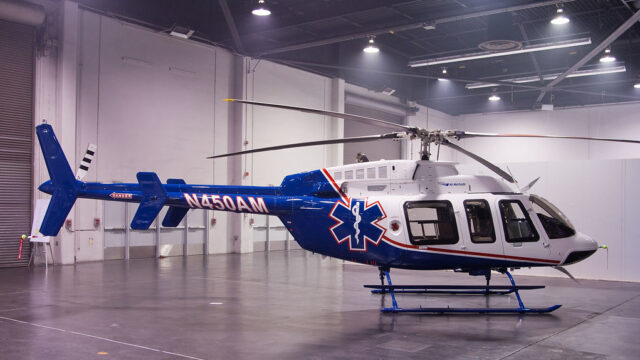 An Air Methods Helicopter, a Bell 407, sits in a hangar unmoving.