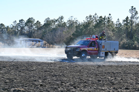 Fire Department brush truck driving through a smoke-filled field