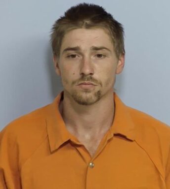 White male with brown hair and short brown facial hair wearing orange jumpsuit
