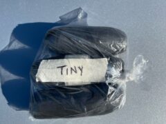 Three packages of cocaine wrapped in black tape made for a body cavity with the label "Tiny".