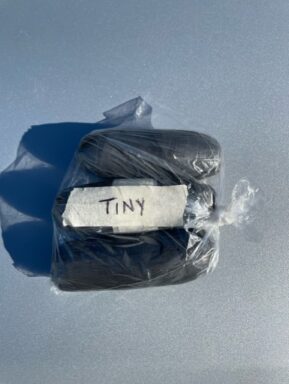 Three packages of cocaine wrapped in black tape made for a body cavity with the label "Tiny".