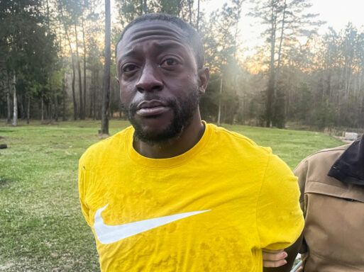 Black male wearing a bright yellow T-shirt with his arms behind his back