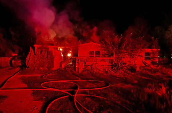 Single wide mobile home with flames coming from left side of house