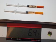 Two syringes on a scale with a reading of 6.4 ounces