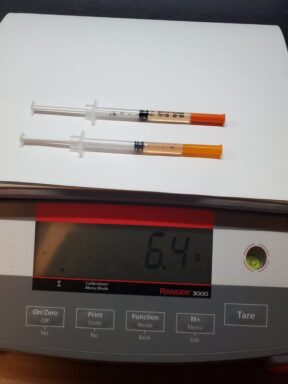 Two syringes on a scale with a reading of 6.4 ounces