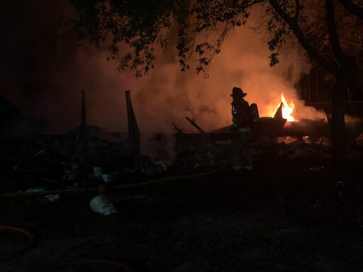 Firefighter standing in the midst of rubble and flames in the dark