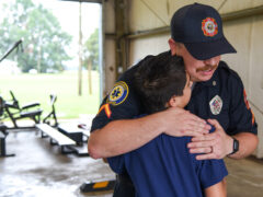 White male paramedic hugging young boy with dark brown hair