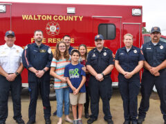 Young boy and his family standing with the EMTs and paramedics who saved his life
