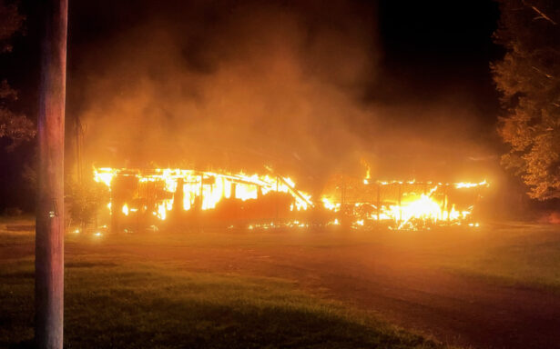 Double-wide mobile home fully engulfed in flames at night