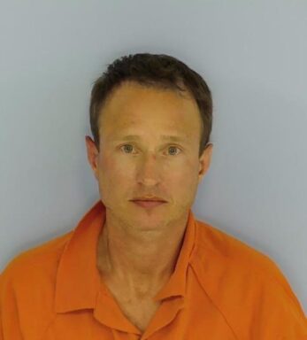 Mug shot of a white male with an orange jumpsuit with brown hair and no facial hair. 