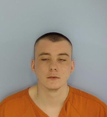 Mug shot of a white male with short brown hair and an orange jumpsuit.