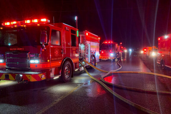 Large red fire trucks with red and white lights lining the roadway