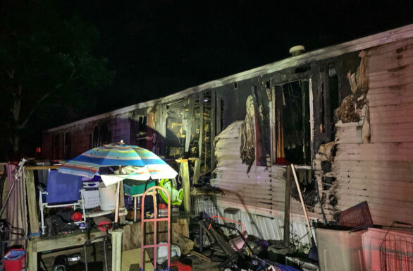 Light colored single-wide mobile home with fire damage