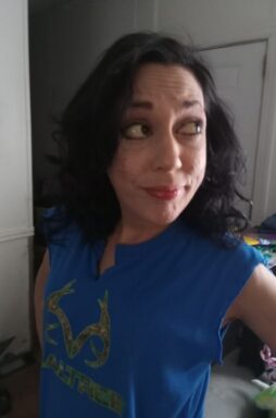 Photo of a white woman with black hair wearing a blue shirt and red lipstick.