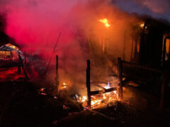 Smoke and heavy debris from a burned down single story home at night
