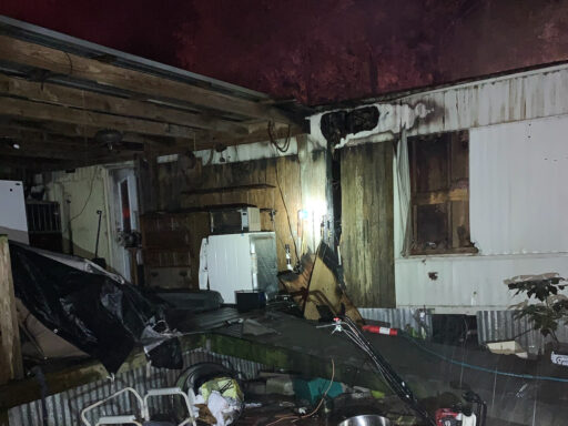 White single-wide mobile home with fire damage