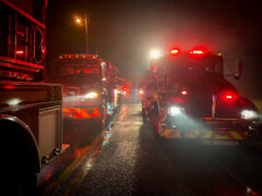 Fire engines with red and white lights lined up in a road at night