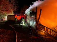 Firefighters outside home spraying water on a house on fire at night