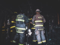 Group of firefighters standing in the rubble after a structure fire