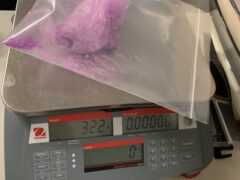 A purple powdery substance in a plastic bag on top of a scale that reads 32.2 grams.