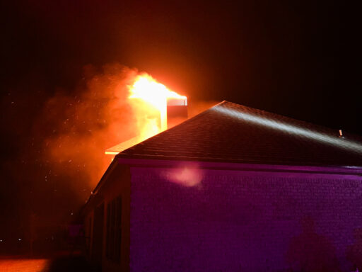 Fire coming out of a chimney in a brick home at night