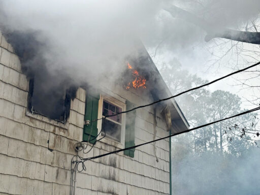 Close up of smoke and flames coming from a window of a home