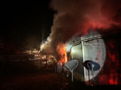 Heavy smoke and flames coming from a double wide mobile home at night
