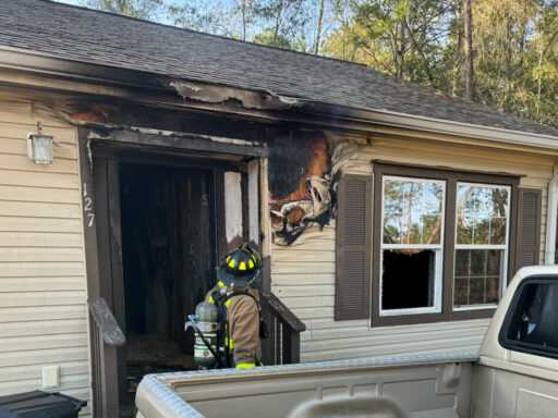 Firefighter looking at smoke damage around the front door of a single story home