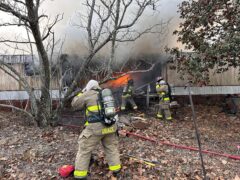 Firefighters outside of single wide mobile home fire