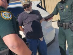 Deputies arresting an older gray haired man and putting