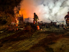 Firefighter standing on top of the debris and in the smoke left after a mobile home fire