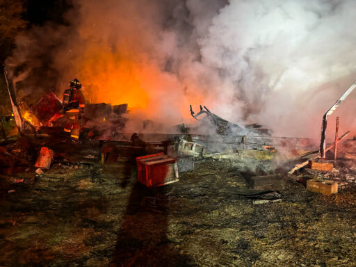 Firefighters in the rubble working to extinguish a fire that destroyed a mobile home