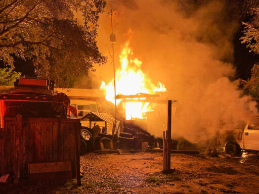 Flames coming from the front of a single-wide mobile home at night
