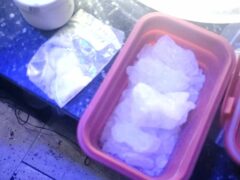 White crystal like substance in a red tub with some aluminum foil next to.